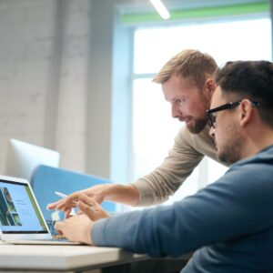 A person showing something on a computer to another person, Marketing Coordinator